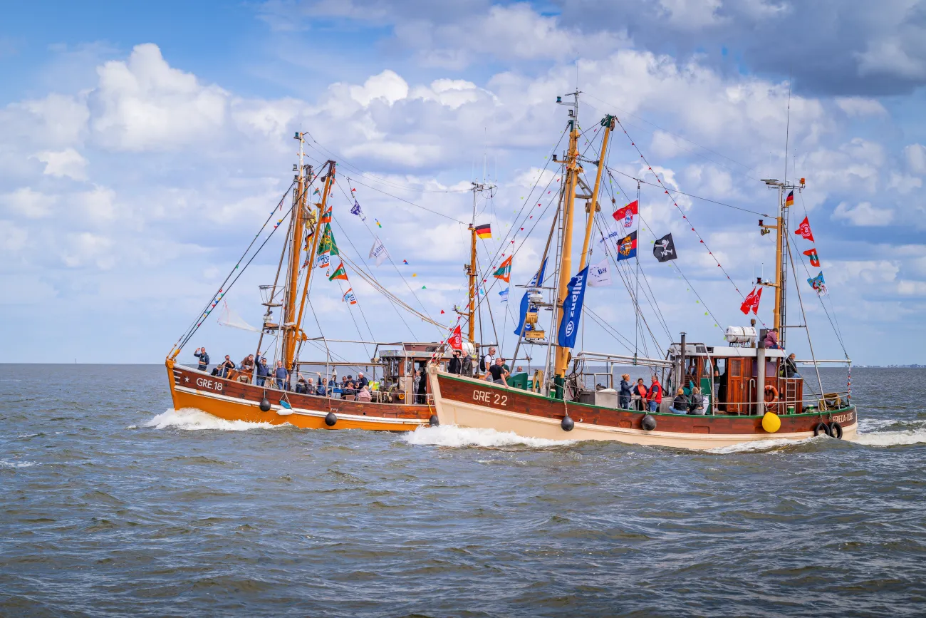 Zwei festlich geschmückte Fischkutter fahren nebeneinander über das Meer vor Greetsiel.
