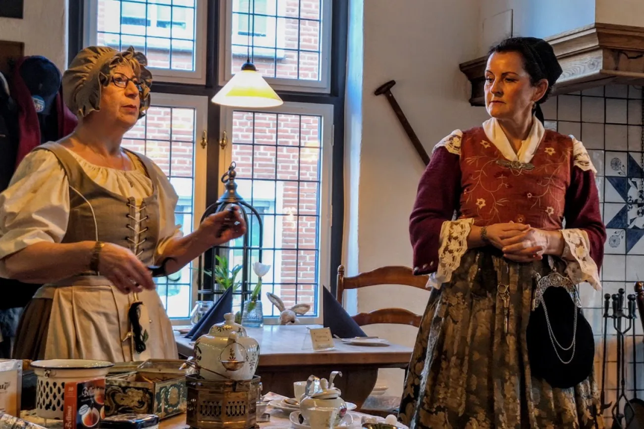 Zwei Frauen in historischer Kleidung erzählen bei Tee und Gebäck Geschichten in plattdeutscher Sprache.