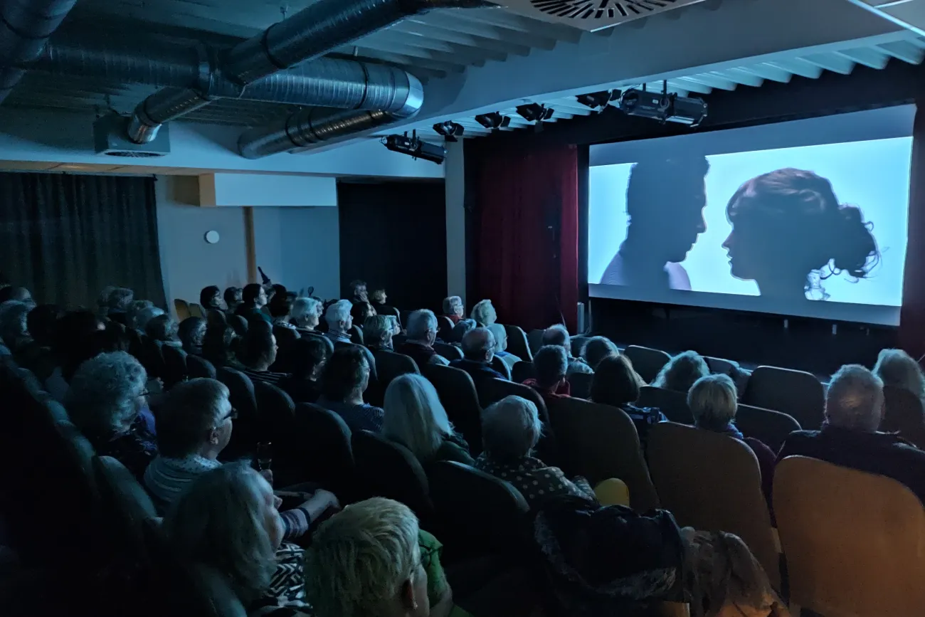 Ein vollbesetztes Kino zeigt eine Projektion von zwei Personen in einem intensiven Profilmoment.