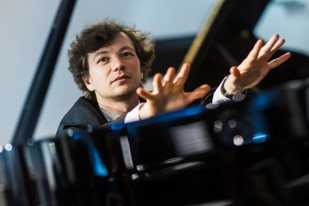 Pianist Mikhail Mordvinov am Flügel mit erhobenen Händen.