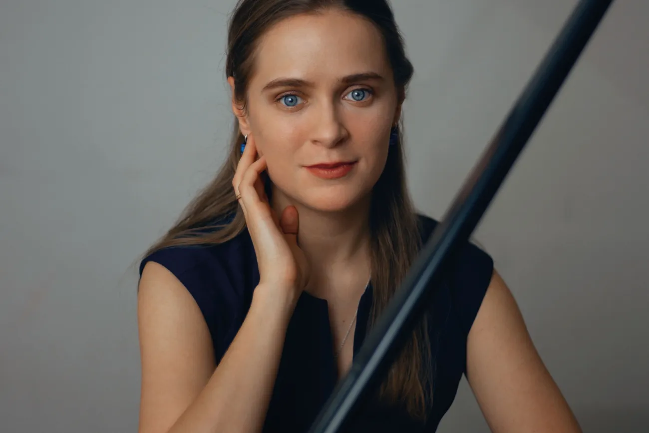 Porträt der Pianistin Anastasia Churbanova am Flügel vor hellem Hintergrund.