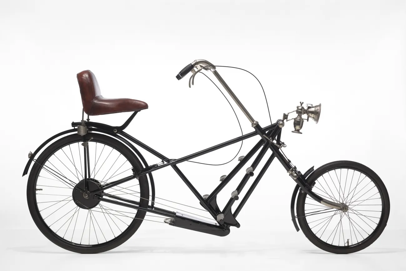 Schwarzes historisches Sesselrad von 1922 mit kleinem Vorderrad und braunem Ledersitz mit Lehne.