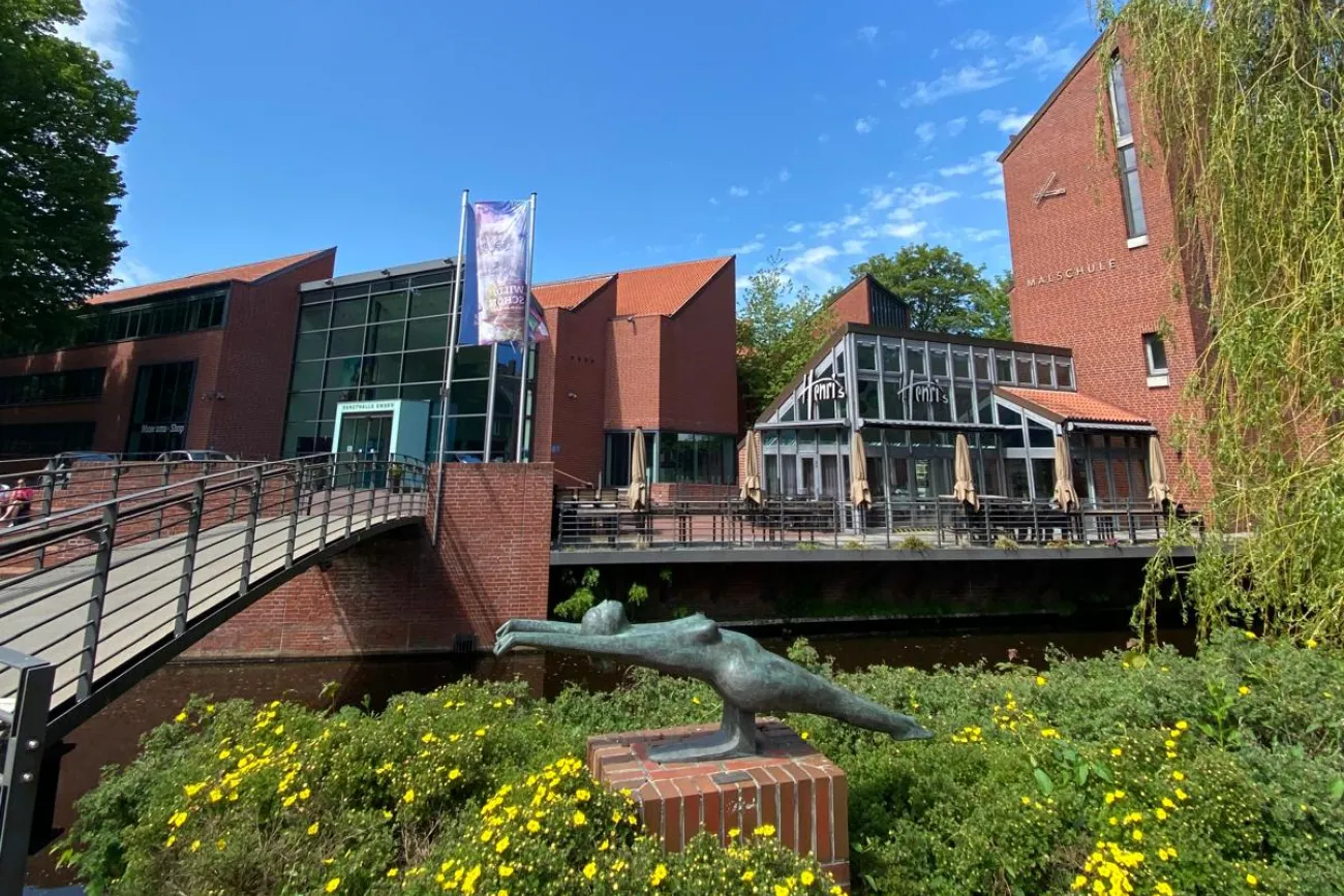 Außenansicht der Kunsthalle Emden, im Vordergrund eine Skulptur in gelben Blumen.
