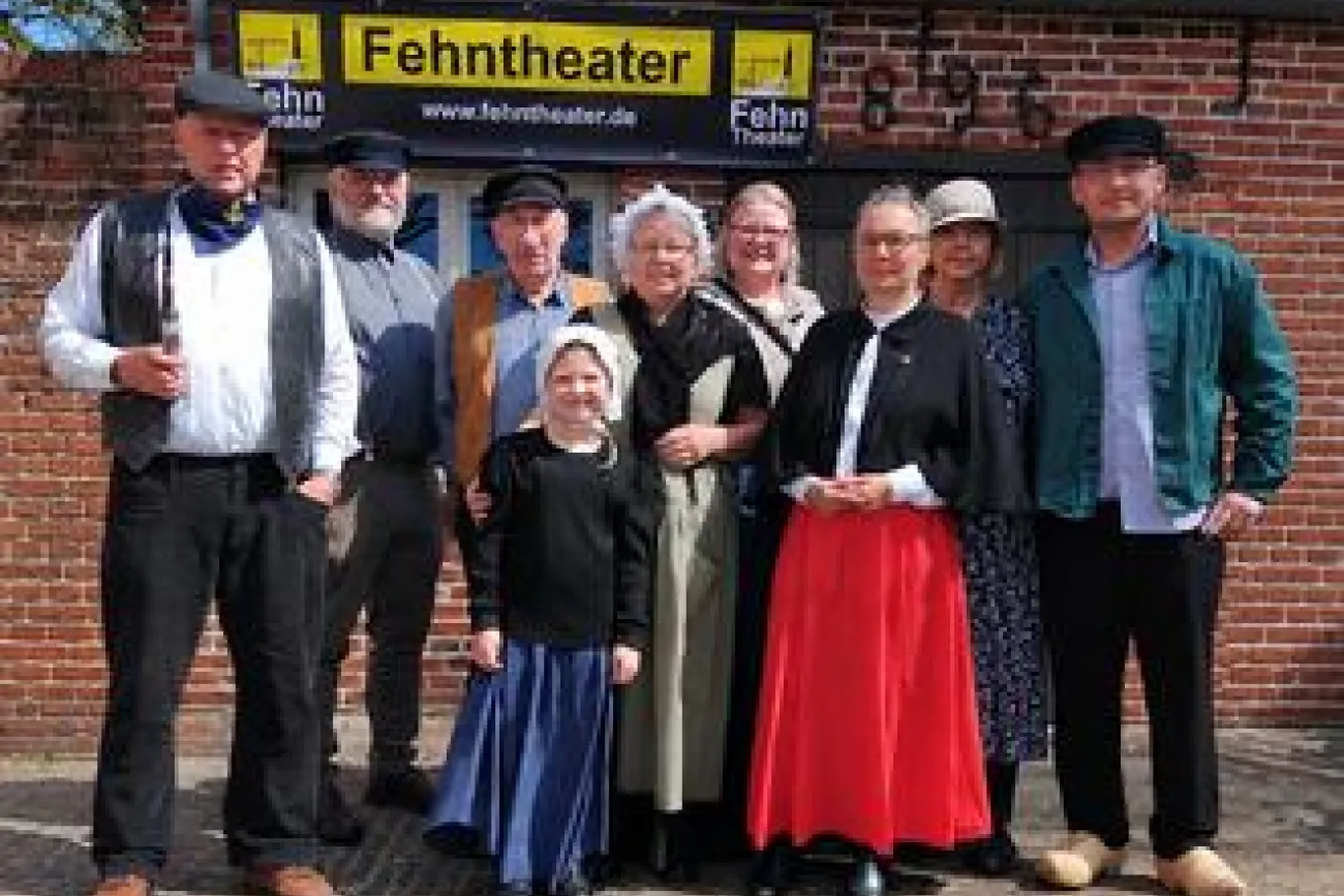 Ensemble des Fehntheaters in historischen Kostümen vor Backsteinfassade.