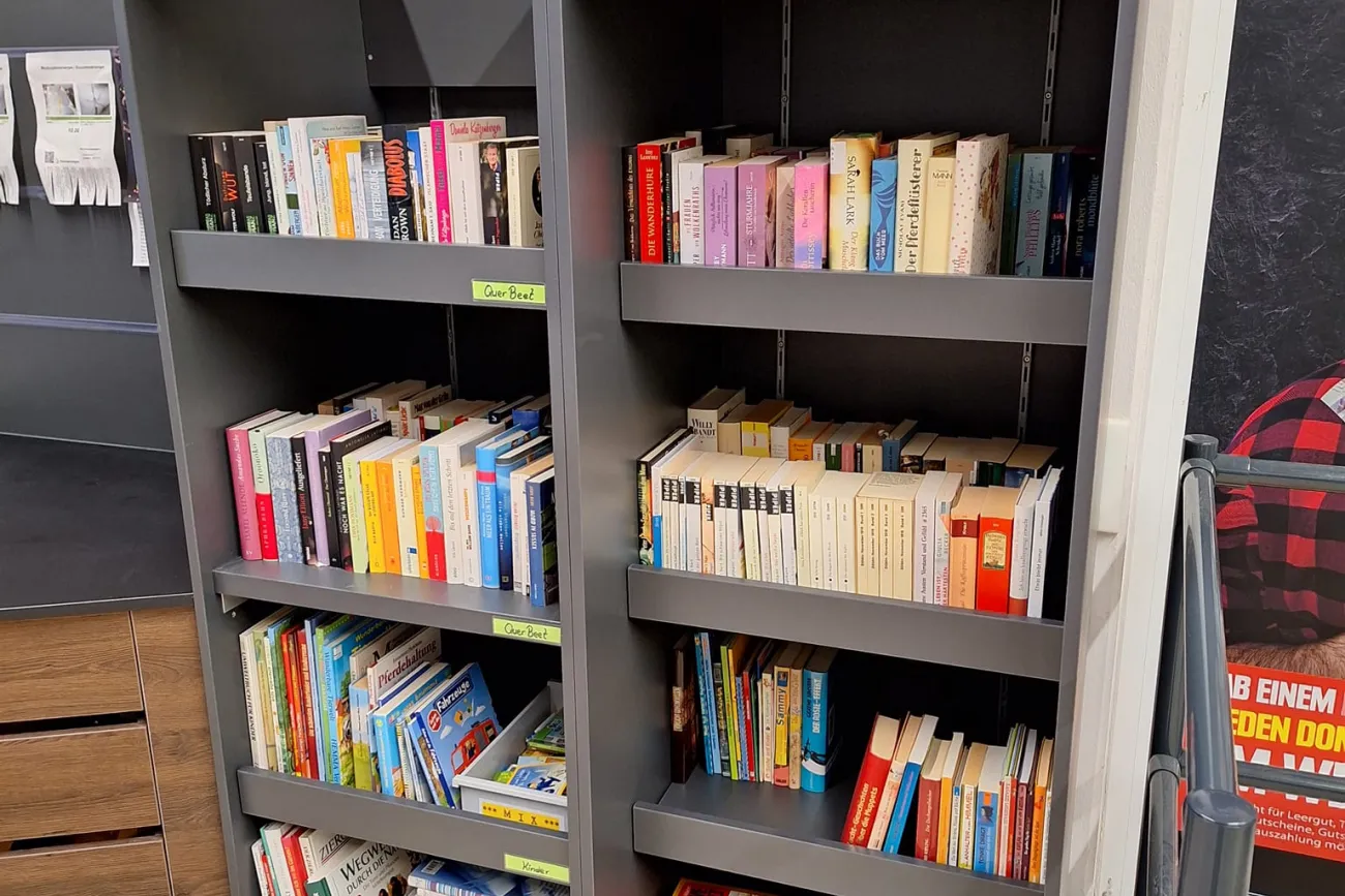 vierstöckiger befüllter Bücherschrank mit Büchern stehend und liegend im E-Center Rhauderfehn