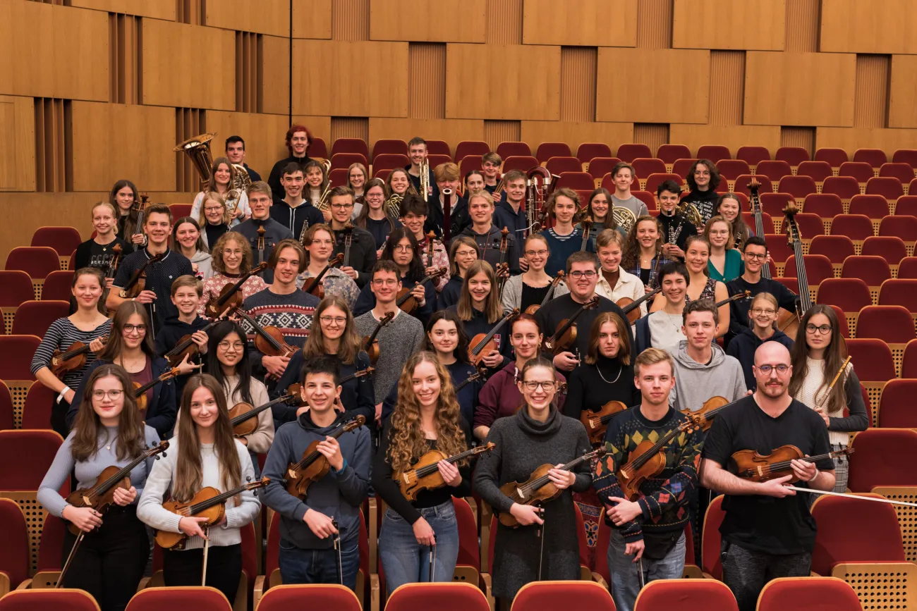 Junges Orchester sitzt in einem Theater Saal.