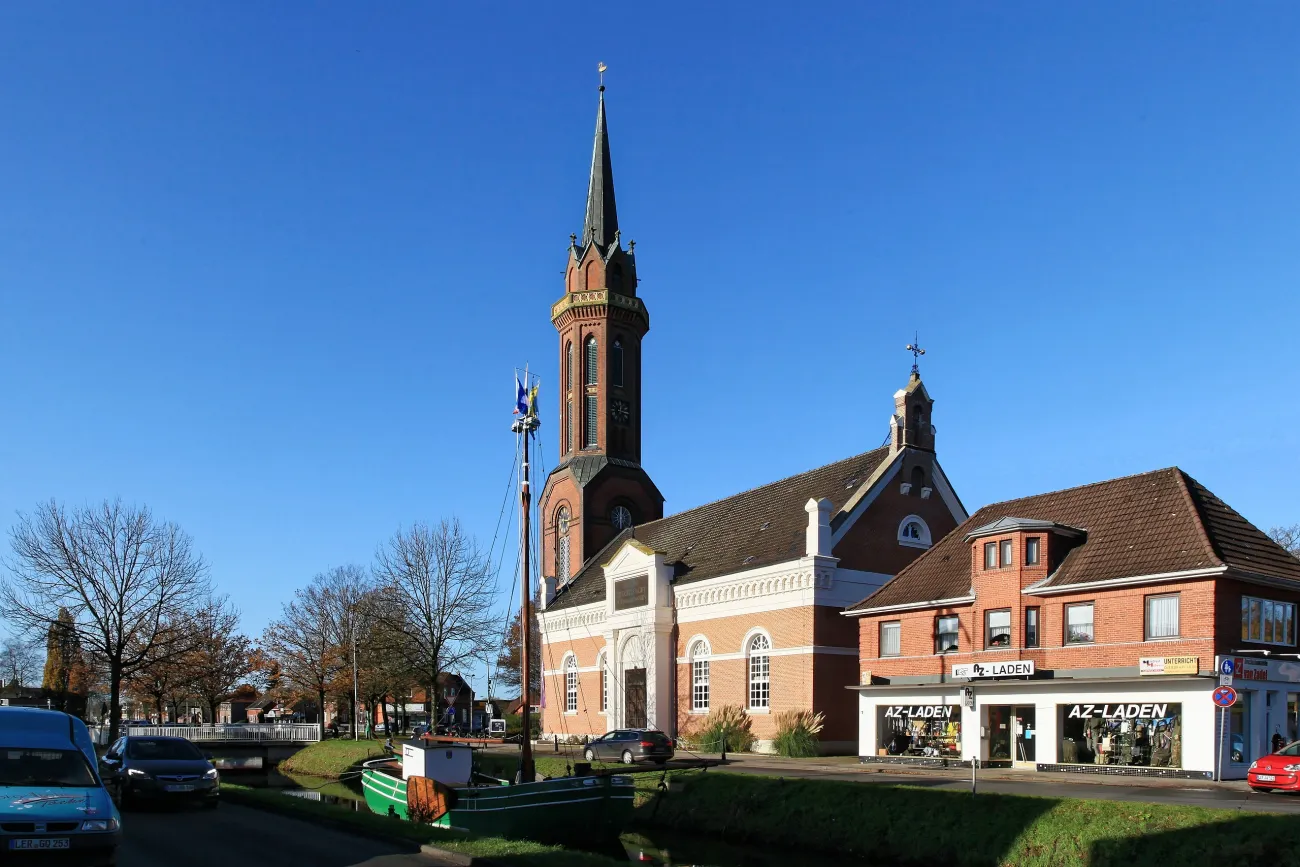 Bild einer Tjalk, im Hintergrund die Hoffnungskirche Rhauderfehn