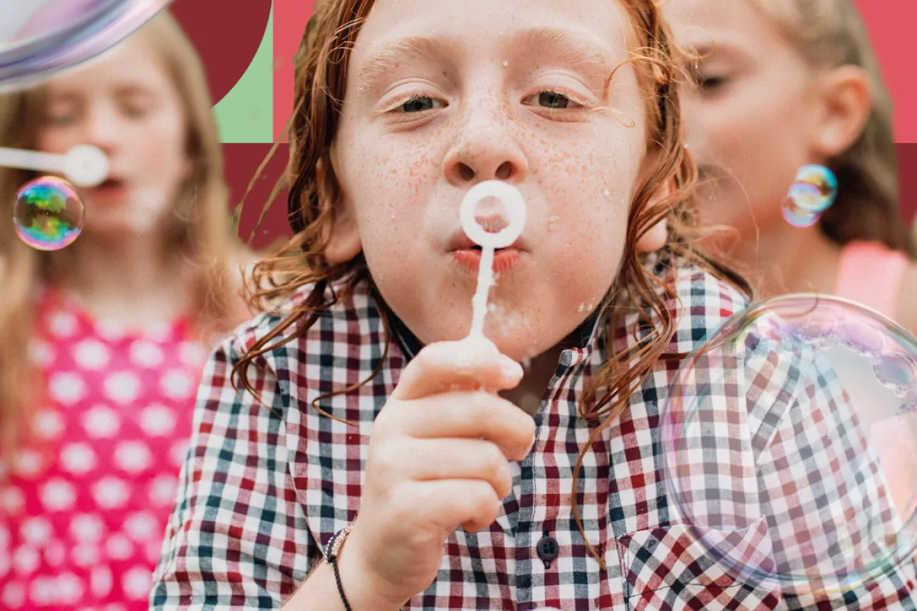 Junge, der mit anderen Kindern Seifenblasen bläst