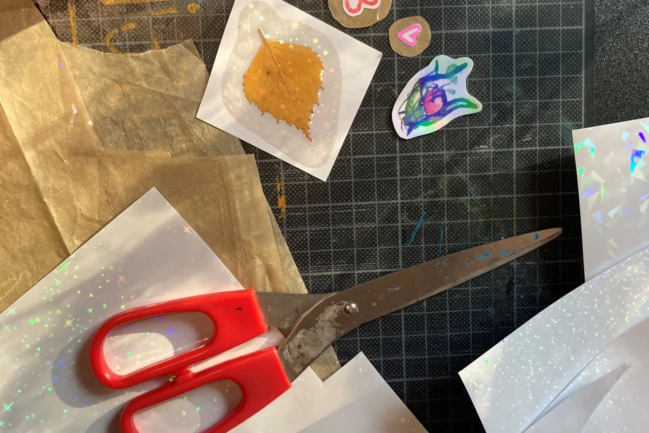 Schere, Blatt und andere Bastelmaterialien liegen auf einem Tisch