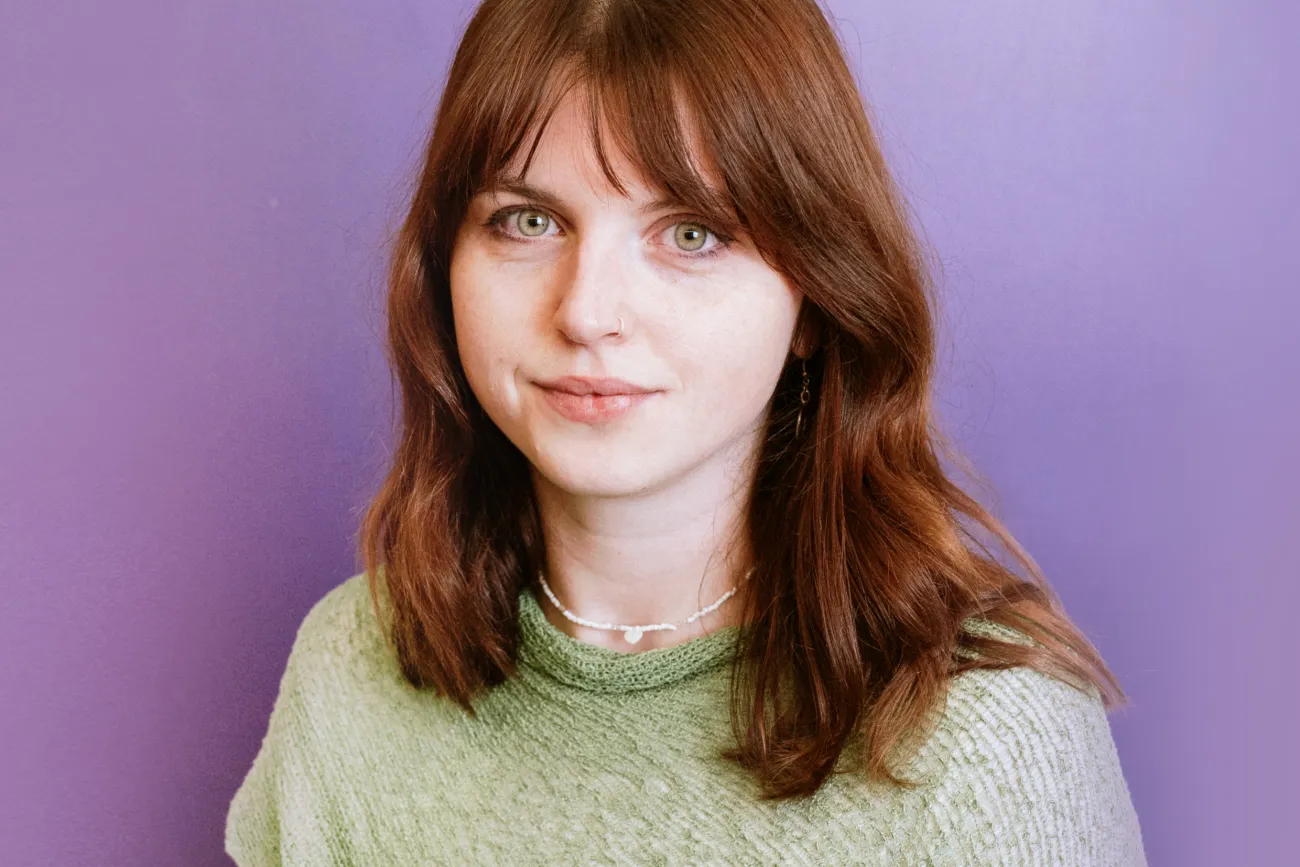 Frau mit brauen Haare vor einem violettem Hintergrund