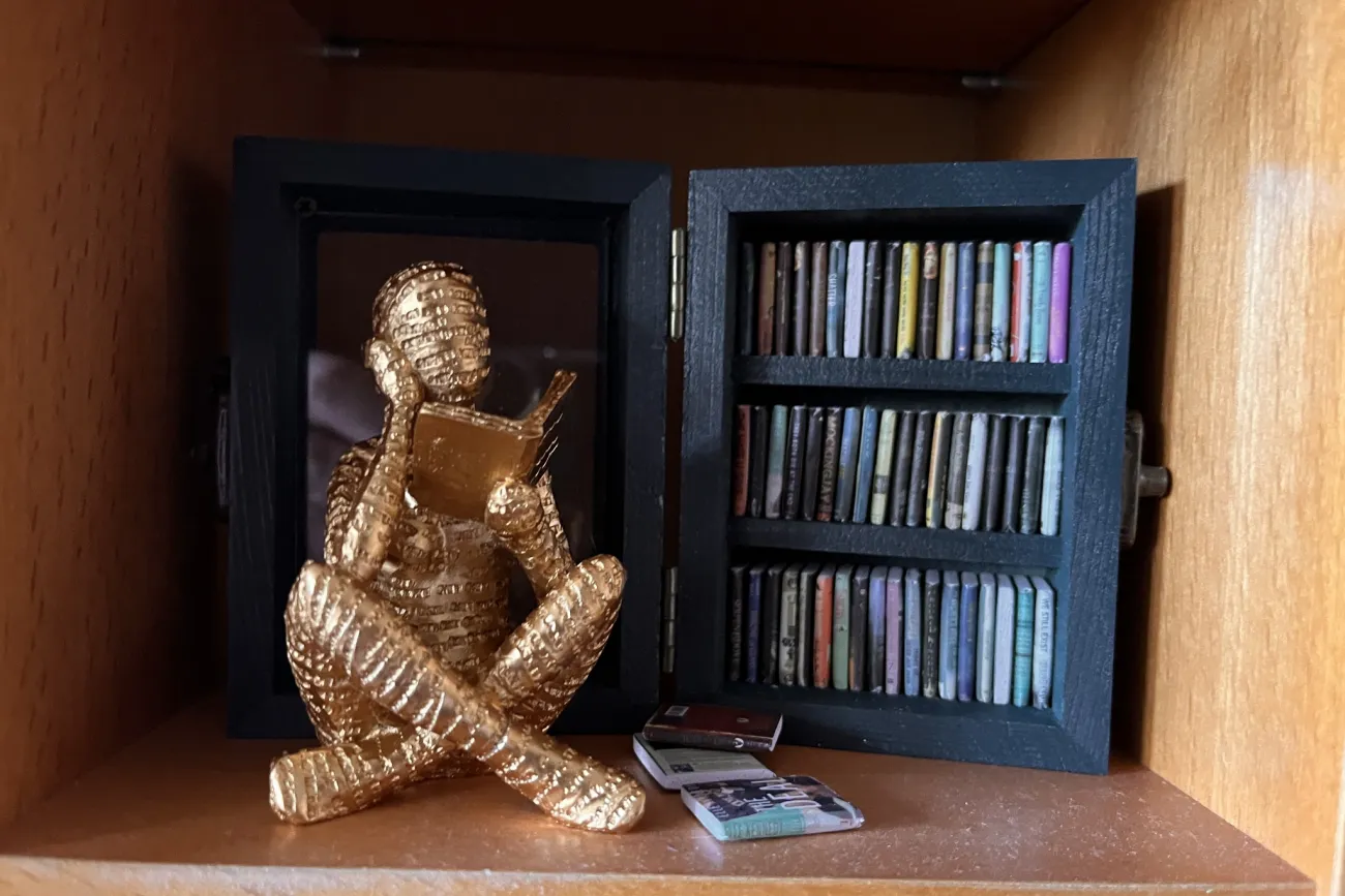 Lesende goldene Figur vor Bücherregal