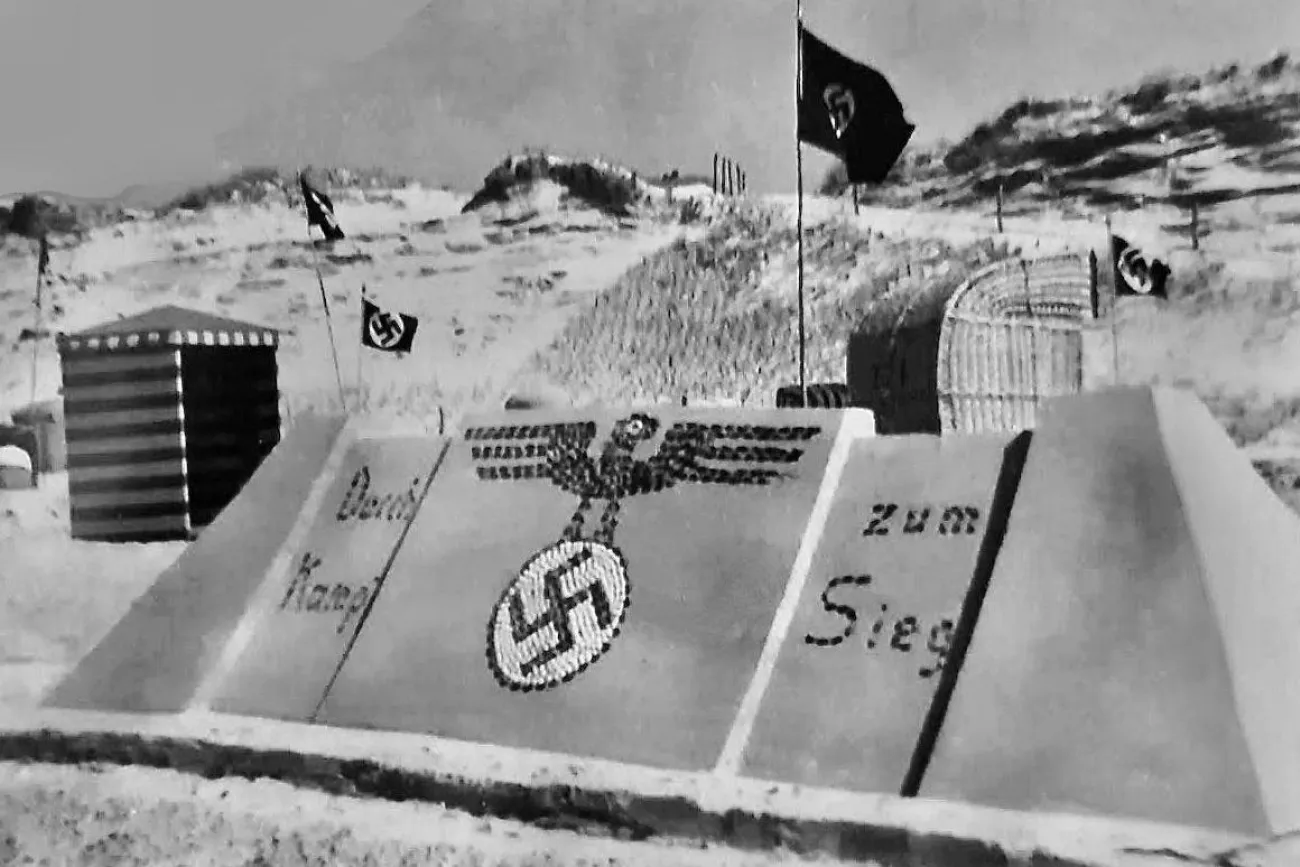 Sandburg auf Langeoog mit nationalsozialistischer Parolen und NS-Symbol aus Muscheln sowie Hakenkreuzflaggen