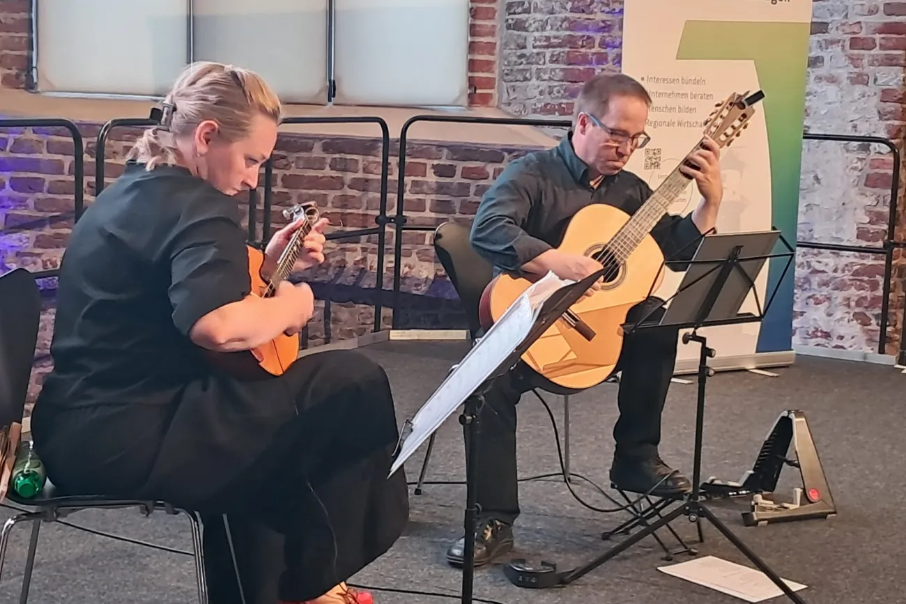 auf einer Bühne spielen eine Frau mit Domra und ein Mann mit Gitarre