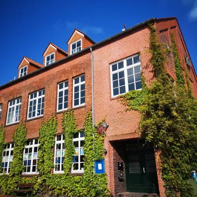 Außenansicht eines großen Gebäudes mit großen Fenstern und mit Efeu bewachsen