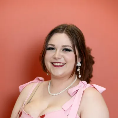 Lächelnde Frau mit braunem Zopf vor einem roten Hintergrund