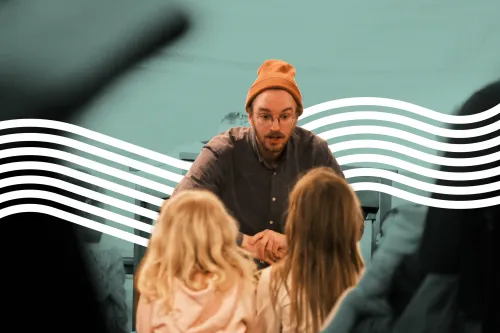 Junger Mann mit Hut erzählt einer Gruppe von Kindern eine Geschichte