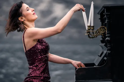Pianistin Nadejda Vlaeva im roten Paillettenkleid am Klavier, welches mit weißen Kerzen dekoriert ist.