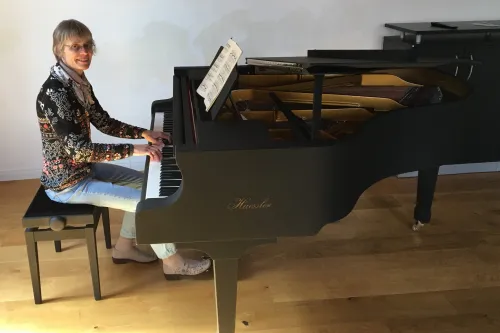 Annette Liss spielt auf einem schwarzen Haessler-Flügel in hellem Raum.