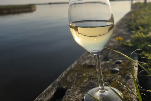 ​Weinglas am Ufer des Großen Meer bei untergehender Sonne an einem Sommerabend. 