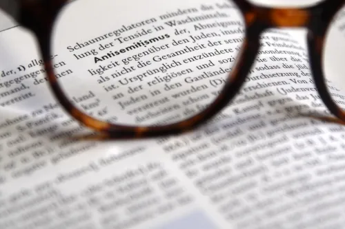 Brille fokussiert den Lexikonbegriff Antisemitismus auf einer aufgeschlagenen Seite.