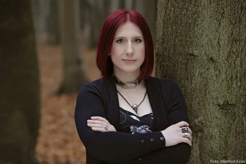 Auf dem Bild sieht man Lydia Benecke in einem Wald angelehnt an einem Baum.