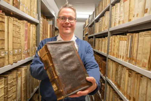 Dr. Heiko Suhr zeigt ein beschädigtes Buch aus der Bibliothek von Christoph Friedrich von Derschau