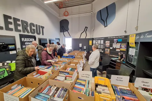 Sechs Tapetentische, darauf Bananenkartons gefüllt mit Büchern