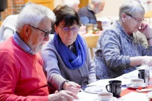 Drei Personen, sitzend, beim Rätseln