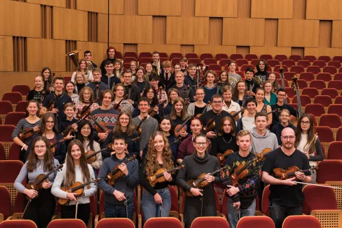 Junges Orchester sitzt in einem Theater Saal.
