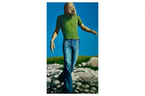 Mann von vorne, grünes T-Shirt, blaue Jeans, auf Steinen laufend