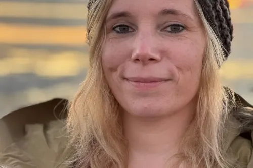 Die Autorin Ilka Gerdes, im Hintergrund sieht man einen Sonnenuntergang an Strand.