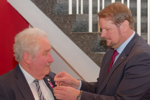 Oberbürgermeister Tim Kruithoff steckt Rico Mecklenburg das Verdienstkreuz ans Revers