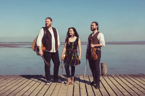 Die Band "La Kejoca" (3 Personen: ein Mann, eine Frau, ein Mann) steht auf einem Steg.