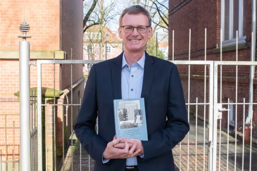 Mann mit Brille zeigt sein Buch