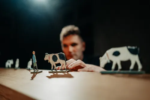 Kuhfiguren und eine menschliche Figur vor einem Figurenspieler