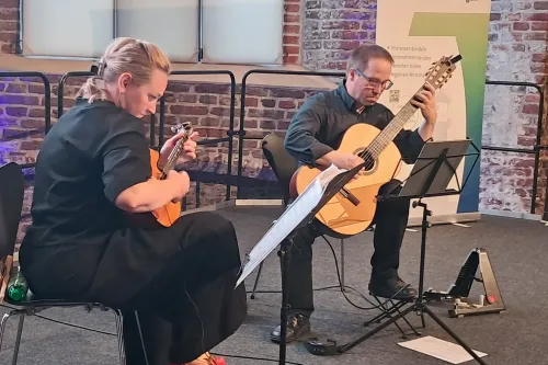 auf einer Bühne spielen eine Frau mit Domra und ein Mann mit Gitarre