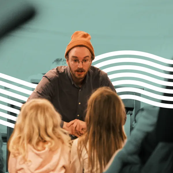 Junger Mann mit Hut erzählt einer Gruppe von Kindern eine Geschichte