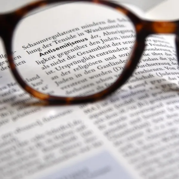 Brille fokussiert den Lexikonbegriff Antisemitismus auf einer aufgeschlagenen Seite.