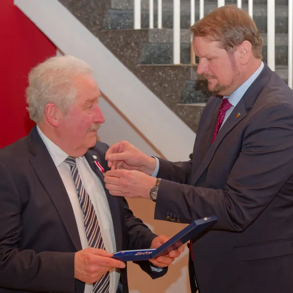 Oberbürgermeister Tim Kruithoff steckt Rico Mecklenburg das Verdienstkreuz ans Revers