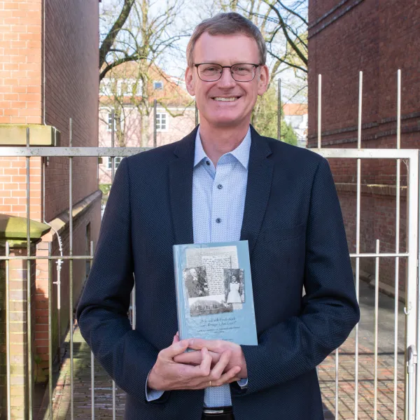 Mann mit Brille zeigt sein Buch
