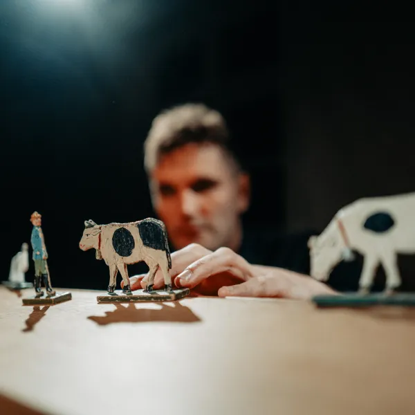 Kuhfiguren und eine menschliche Figur vor einem Figurenspieler