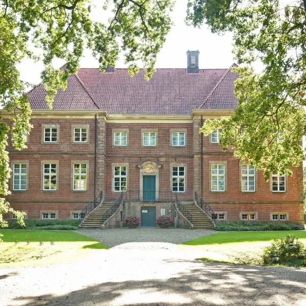 Das Herrenhaus hinter großen Eichen leicht verdeckt