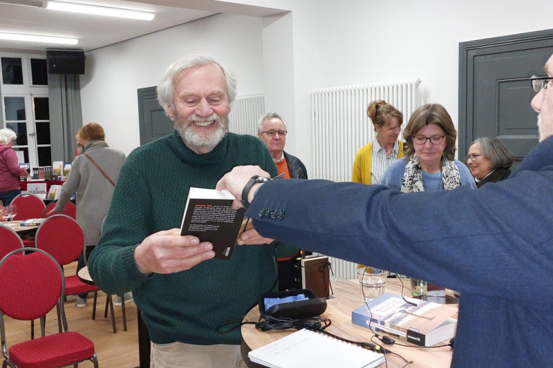 Nach einer Lesung signiert ein Buchautor seine Werke. 