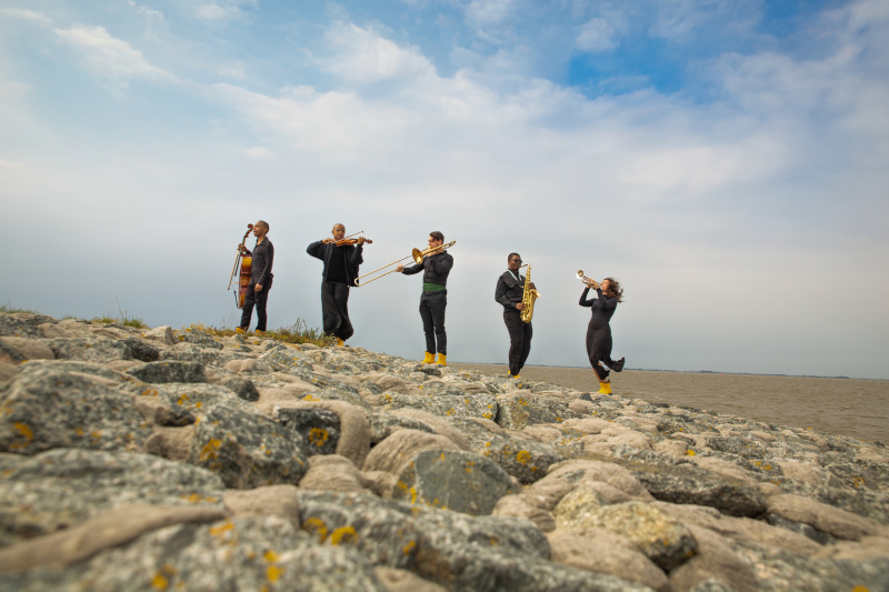 Musiker und Musikerinnen mit Instrumenten am Strand
