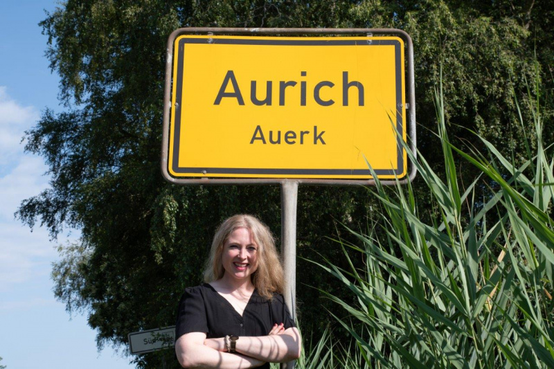 Grietje Kammler mit einem der Ortsschilder von Aurich / Auerk