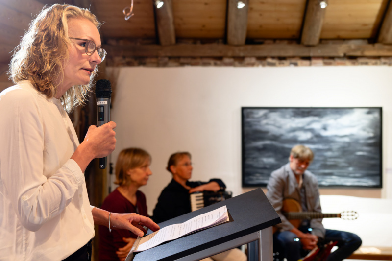 Sarah Byl hält die Laudatio, im Hintergrund: Das DreiBartLang-Trio