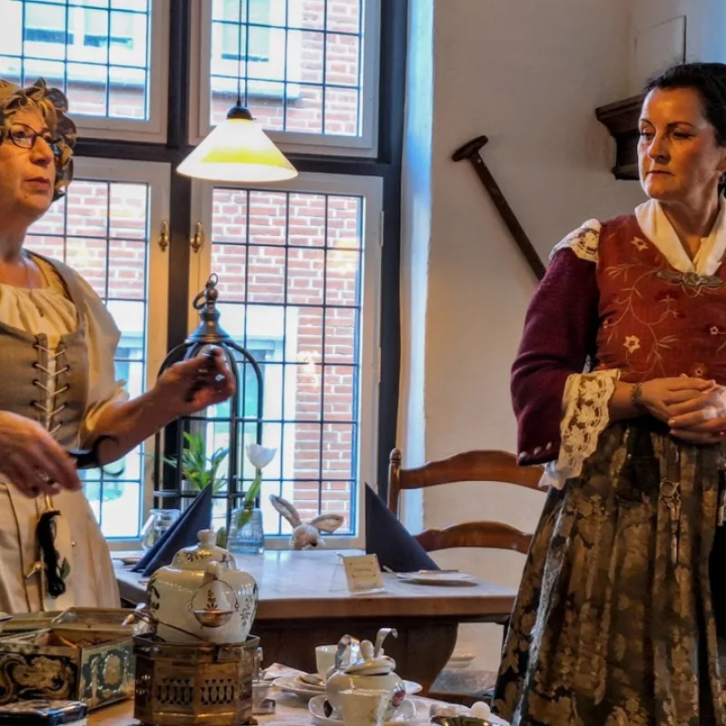 Zwei Frauen in historischer Kleidung erzählen bei Tee und Gebäck Geschichten in plattdeutscher Sprache.