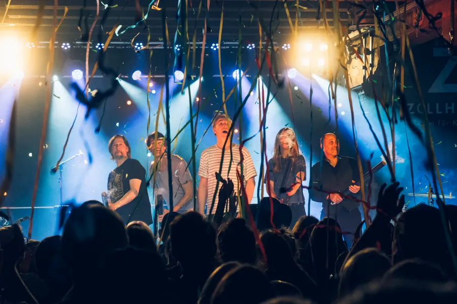 Band steht hinter einem Luftschlangenregen auf der Bühne