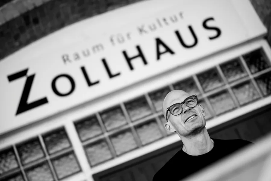 Mann mit Brille vor dem Spruch "Raum für Kultur. Zollhaus"