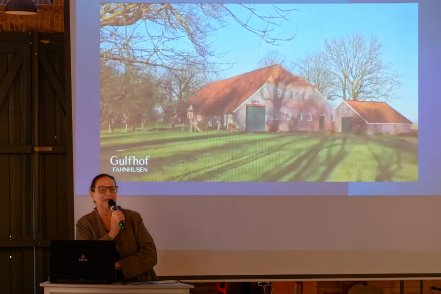 Luise Fauerbach-Geiken bei ihrem Vortrag „Alte Seele, neue Nutzung“. Im Bild hinter ihr ist der frisch sanierte Gulfhof „Fahnhusen“ zu sehen.